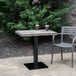 A Grosfillex Vanguard vintage pine table top with two plastic cups on it on a patio.