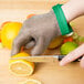 A person cutting a lemon with a San Jamar stainless steel mesh glove.