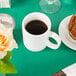 A hunter green table cover with a white mug of coffee and a muffin on a table.