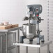 An Avantco planetary stand mixer with standard accessories on a table.