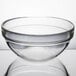 An Arcoroc clear glass bowl on a white surface.