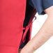 A person's arm holding a red Intedge cobbler apron with two pockets.