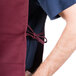 A man wearing a burgundy Intedge cobbler apron with two pockets.