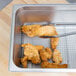 A Vollrath stainless steel wire pan grate with fried chicken on it.