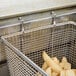 A Pitco twin fryer basket filled with french fries on a counter.