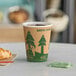 A close-up of an EcoChoice Kraft paper hot cup full of coffee on a table with a croissant.