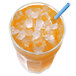 A glass of orange juice with ice and a straw on a table with a blue straw.