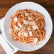 A Milano white melamine bowl filled with spaghetti and cheese with sauce on a table.