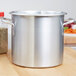 A Vollrath Wear-Ever aluminum stock pot on a wooden surface.