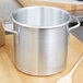 A silver Vollrath Wear-Ever stock pot on a wooden surface.