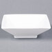 A close-up of a white square porcelain bowl with a square base.