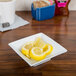 A Bright White Square Porcelain bowl filled with lemon slices on a table.
