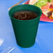 A Hunter Green plastic cup with liquid in it.
