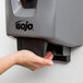 A hand using a GOJO gray soap dispenser.