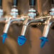 A row of San Jamar Kleen Plugs in blue beer taps.
