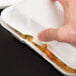 A hand holding a white Genpak styrofoam container with food inside.