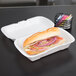 A sandwich in a Genpak white medium shallow foam hinged lid container.