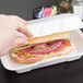 A hand holding a sandwich in a white Genpak foam container.