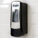 A GOJO® chrome ADX-7 soap dispenser on a tile wall.