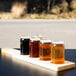 A row of Libbey glass cans filled with beer on a wooden board in a brewery tasting room.