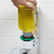 A hand pouring yellow GOJO foam soap into a soap dispenser.