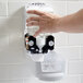 A hand reaching out to a wall mounted white GOJO soap dispenser.