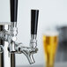 A Beverage-Air black plastic beer tap handle on a silver and black tap with a glass of beer.