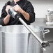 A man in a black chef's jacket using a Waring immersion blender in a professional kitchen.