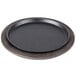 A black round plate on a black metal tray with a wooden base.