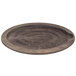 A Lodge oval wooden underliner with a walnut finish under a round wooden plate.