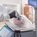 A person in gloves weighing meat on a scale and putting it in a Choice plain plastic deli bag.