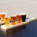 A row of Libbey Mini Pub Tasting Glasses on a table with a natural flight paddle.
