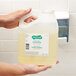 A hand holding a Micrell jug of floral antibacterial lotion hand soap.