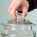 A person holding an Acopa glass beverage dispenser lid