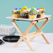 A Tablecraft mini table tray stand with a tray of cupcakes on a table.