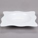 A white square melamine bowl with a wavy design on the edge.