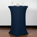 A Snap Drape navy blue spandex table cover on a round bar height table with two wine glasses on it.