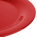 A close-up of a red Carlisle Sierrus melamine plate with a curved edge.