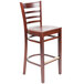 A Lancaster Table & Seating mahogany wood bar stool with a ladder back and mahogany wood seat.