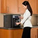 A woman using a Follett countertop ice and water dispenser.