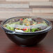 A Fineline clear plastic lid on a salad bowl filled with salad.