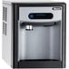 A white Follett countertop ice maker and dispenser with a blue button.