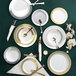 A table setting with Visions white plastic plates with gold lattice design and silverware.