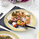 A Visions white plastic plate with gold lattice design holding food on a table.