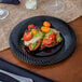 A Visions black plastic plate with food on a table.