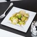 A Visions Florence white plastic plate with a fork and brussels sprouts.