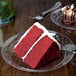 A slice of red velvet cake on a clear plastic plate.