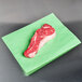 A piece of raw meat on green steak paper.