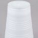 A white Dart Conex plastic cup with a translucent lid on it.