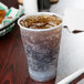 A Dart Conex Galaxy translucent plastic cup filled with soda and ice with a straw.